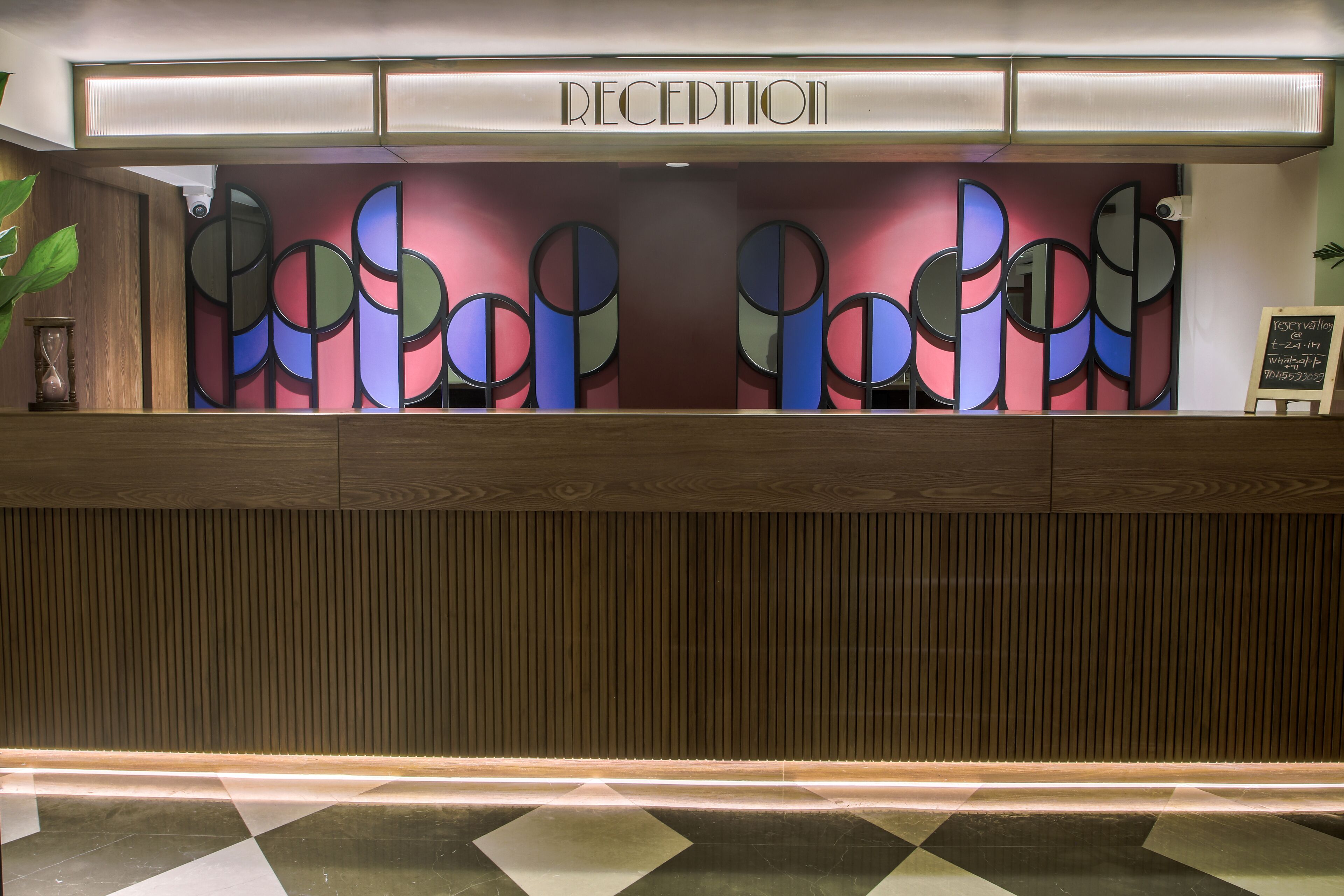 A reception desk with a modern design, featuring a nameplate and a decorative wall with abstract patterns.