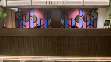 A reception desk with a modern design, featuring a nameplate and a decorative wall with abstract patterns.