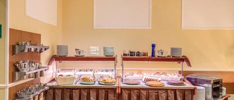 A buffet setup with various food items and utensils.