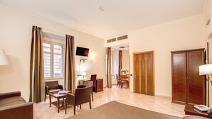 A hotel room with a large bed, a desk with chairs, a TV, and a wardrobe. - Hotel San Marco (Rome)