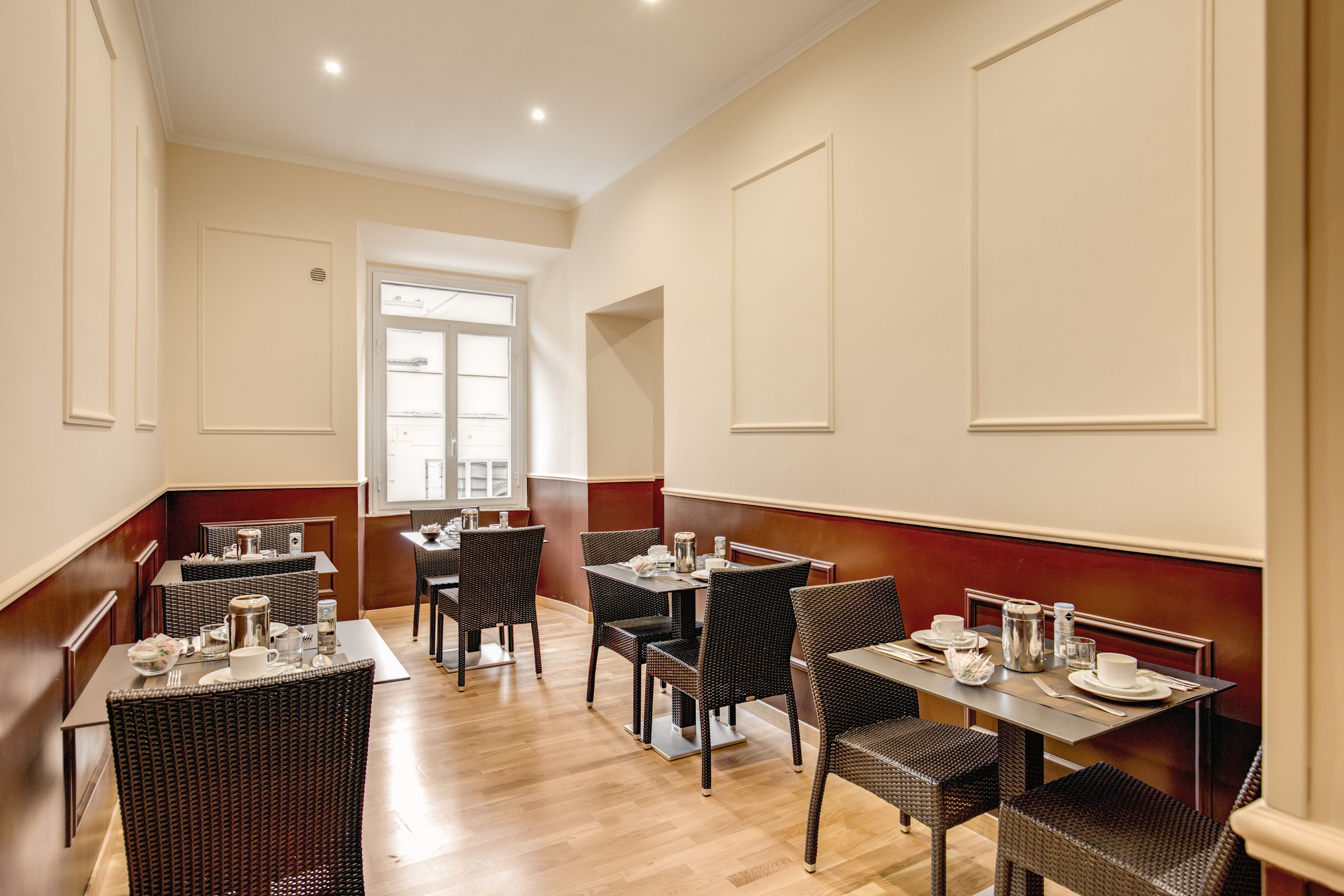 A dining area with multiple tables and chairs, wooden floors, and a view of a window.