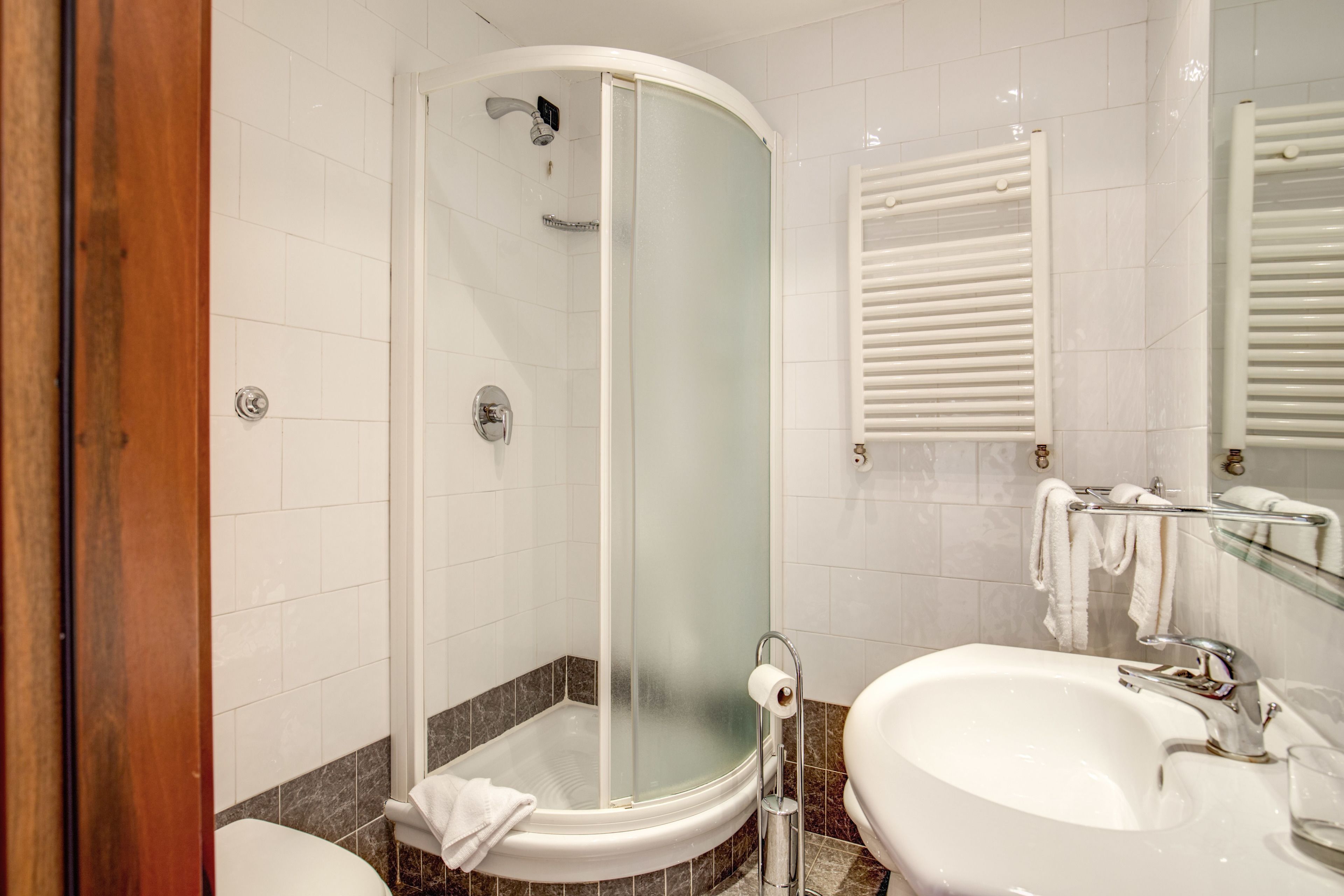 A modern bathroom with a glass-enclosed shower, a white sink, and a mirror with a towel rack.