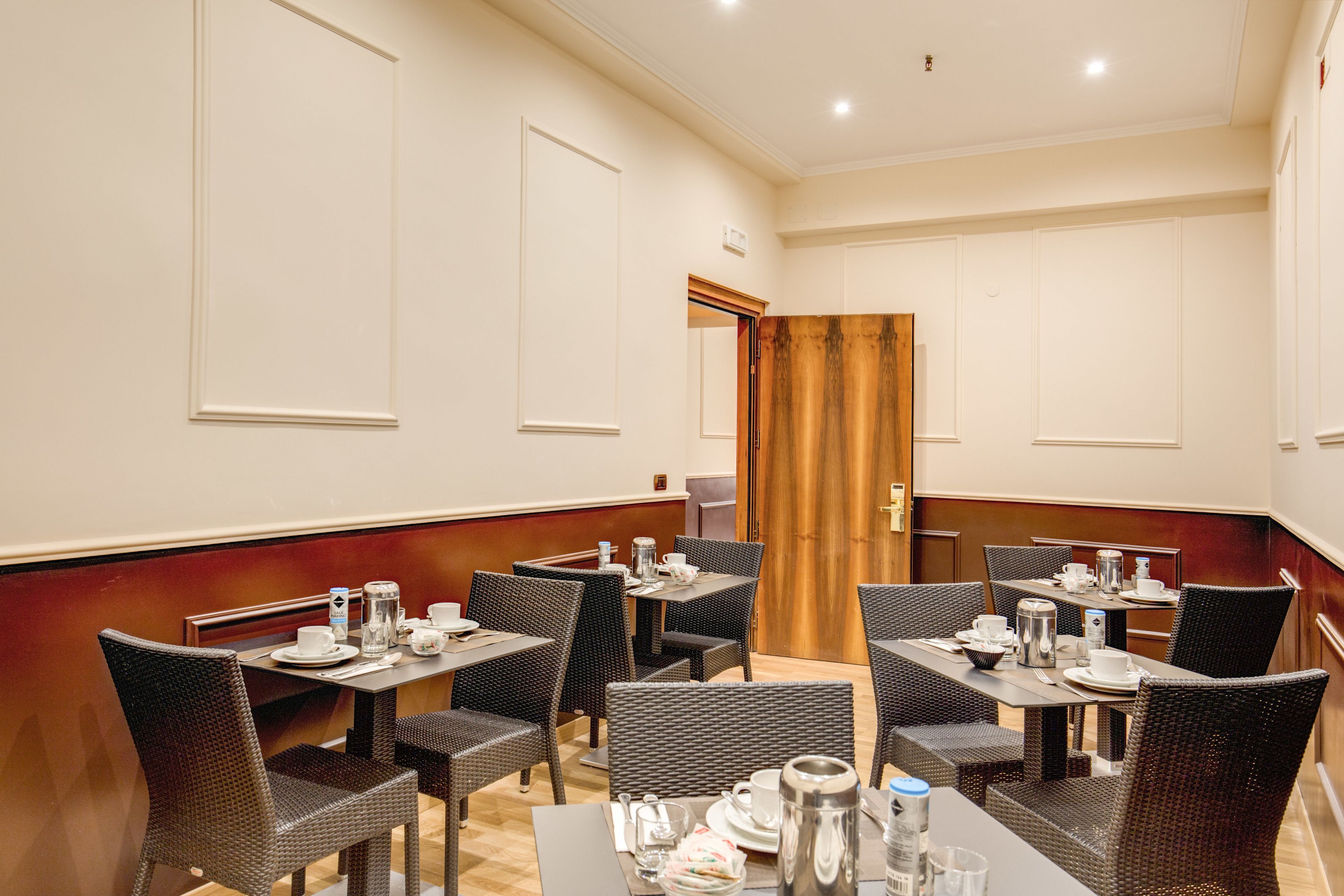 A dining area with tables set for breakfast, including plates, cups, and cutlery.