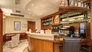 A bar area with a curved wooden counter, bar stools, and a variety of bottles and glasses on shelves. - Hotel San Marco (Rome)