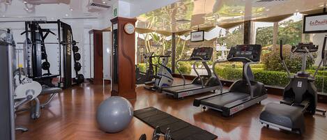 A gym with treadmills, elliptical machines, free weights, and exercise balls.