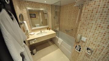 A modern bathroom with a glass-enclosed shower, a large mirror, and a beige tiled wall.