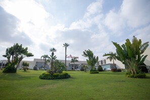 A hotel courtyard with a well-maintained lawn, palm trees, and a building with 'LePassage' signage. - Le Passage Cairo Hotel & Casino (Cairo)
