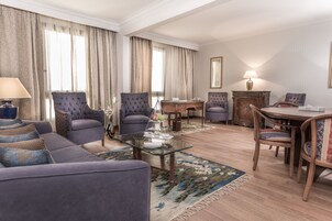 Un salon comprenant un canapé, des fauteuils, une table basse en verre et un coin repas avec une table et des chaises.