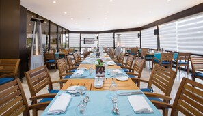 A long dining table with chairs, set with plates, cutlery, and glasses, in a well-lit room with large windows. - Le Passage Cairo Hotel & Casino (Cairo)