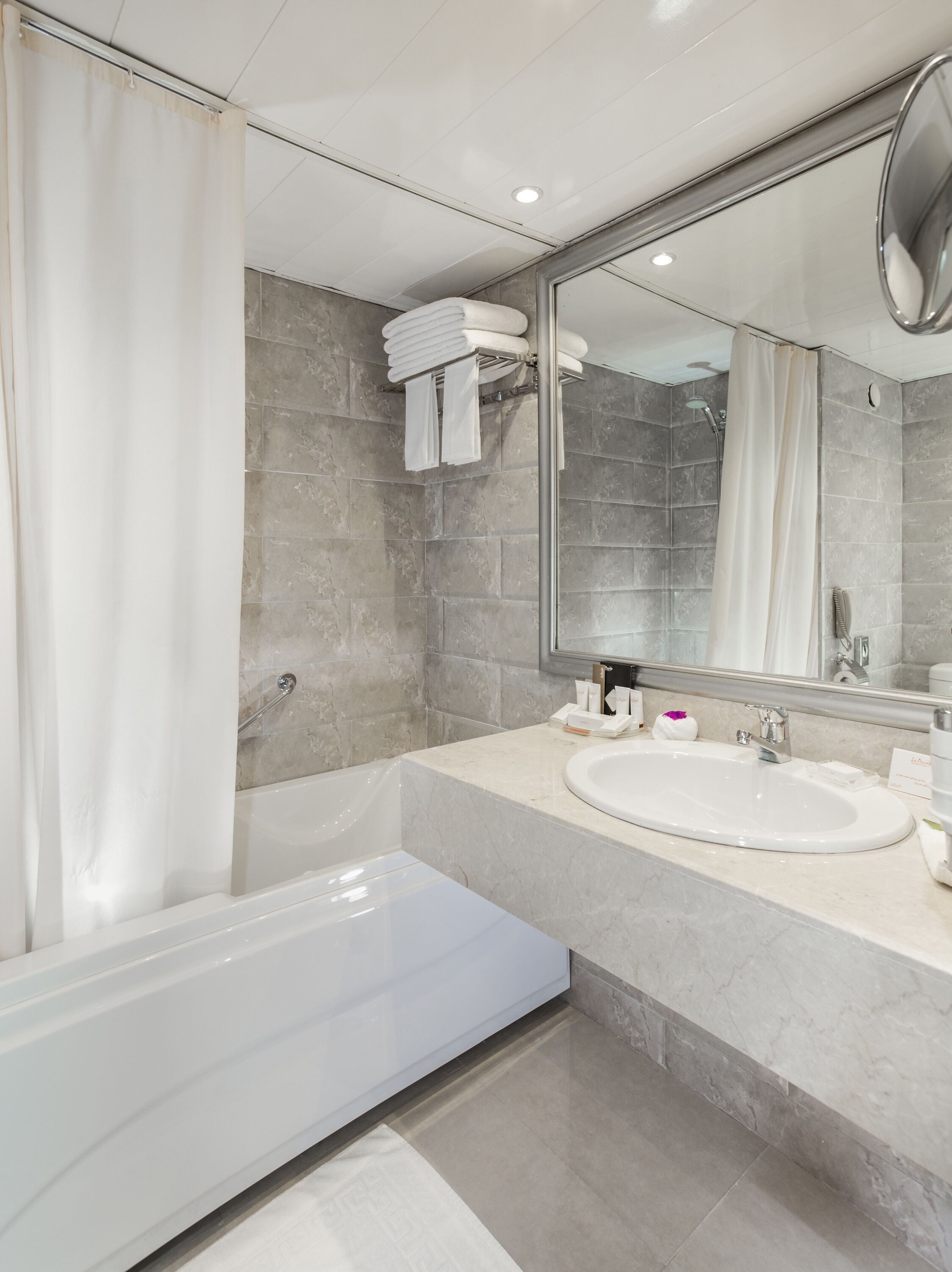 A modern bathroom with a bathtub, a sink, and a large mirror.