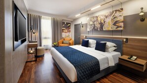 Een moderne hotelkamer met een groot bed, een flatscreen televisie, een nachtkastje met telefoon en een schilderij aan de muur.