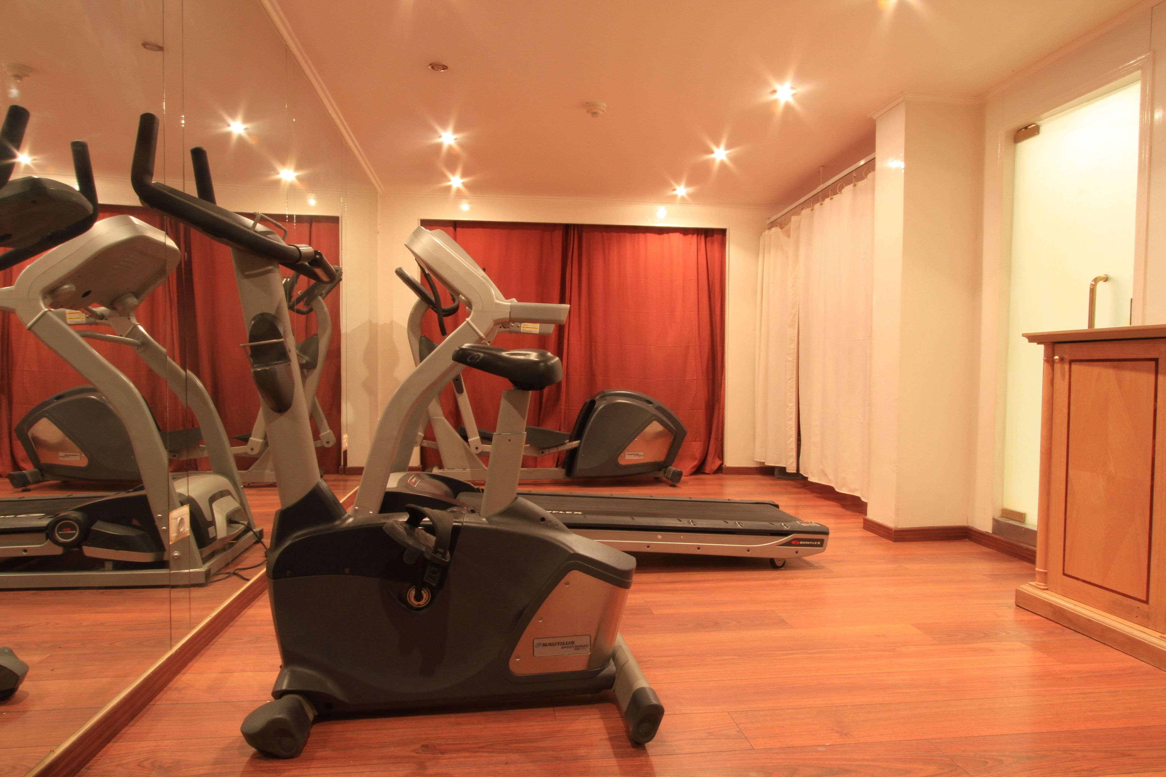 Une salle de sport équipée de vélos d’appartement, de tapis de course et d’un mur recouvert de miroirs.