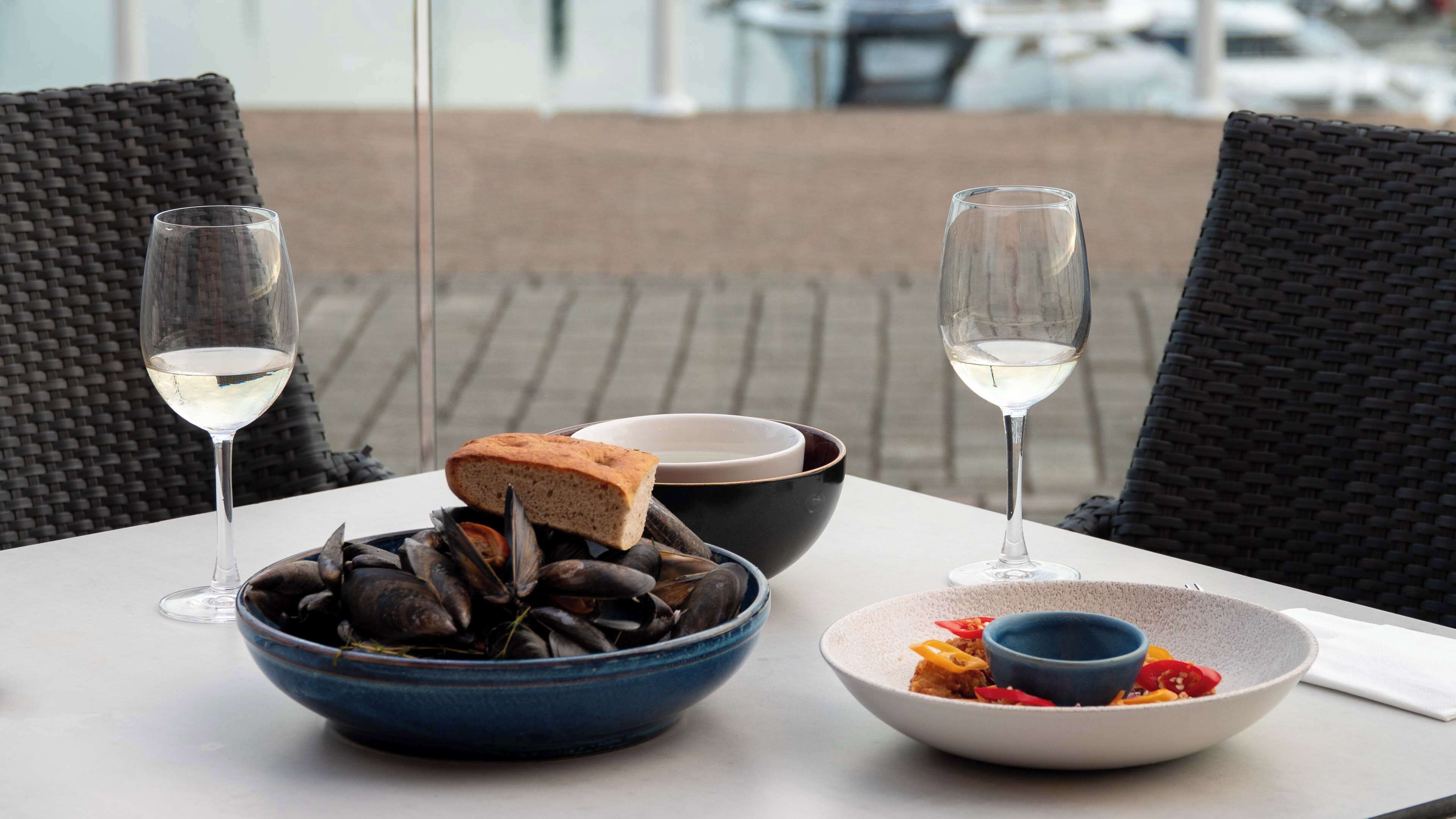 A table with seafood, bread, and drinks, set on an outdoor patio.