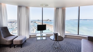 Quarto de hotel com uma grande janela que oferece vista para a marina e o mar.