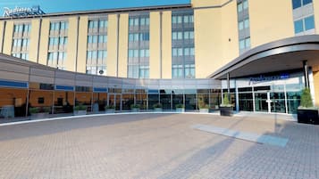 A Radisson hotel with a modern exterior, large glass windows, and a paved courtyard.