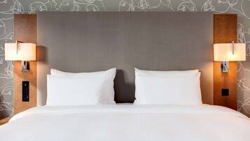 Una habitación de hotel con una cama grande, dos lámparas de noche y una pared con un diseño de peces.