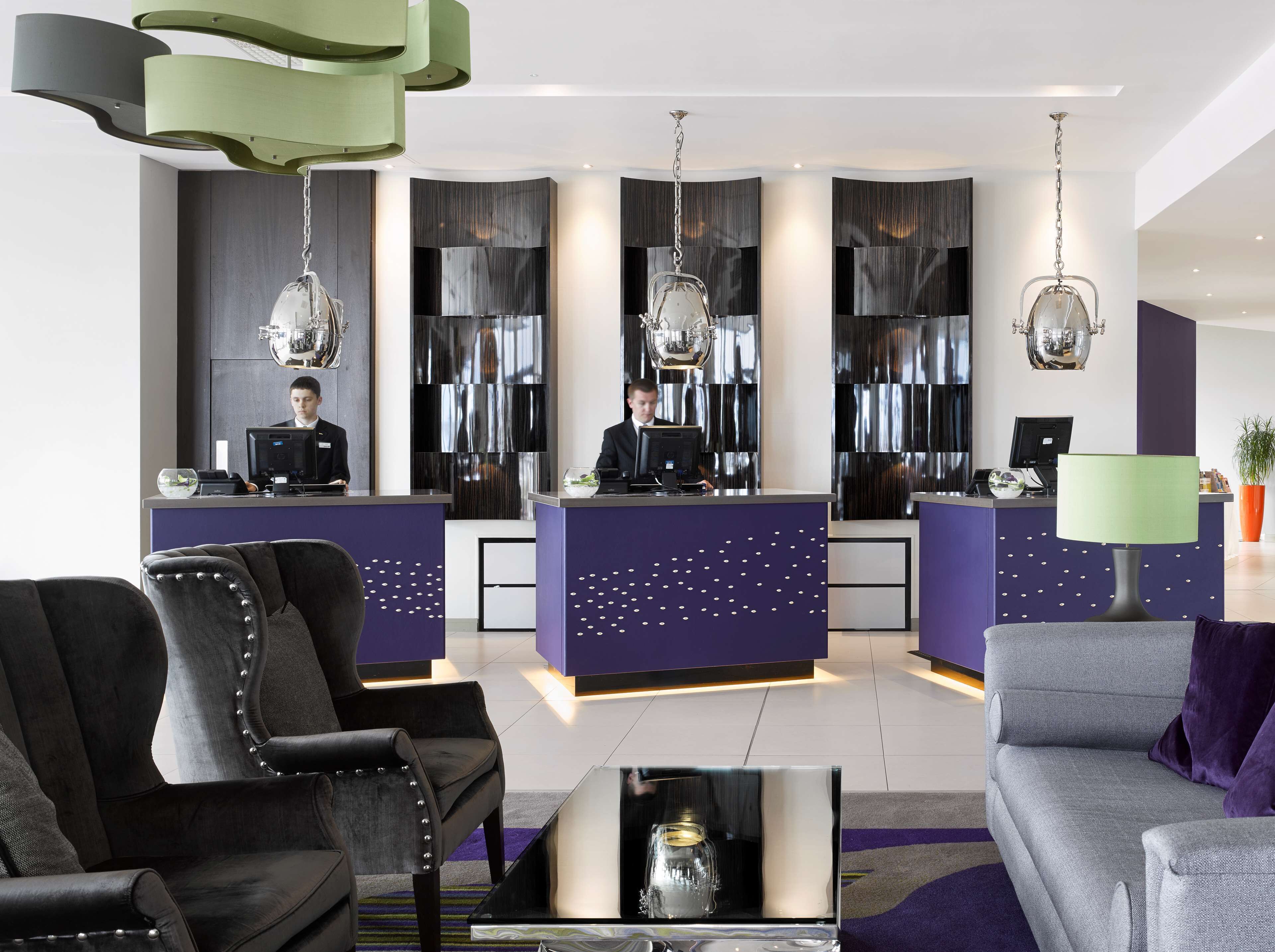 A modern reception area with two receptionists, a purple and black color scheme, and contemporary furniture.