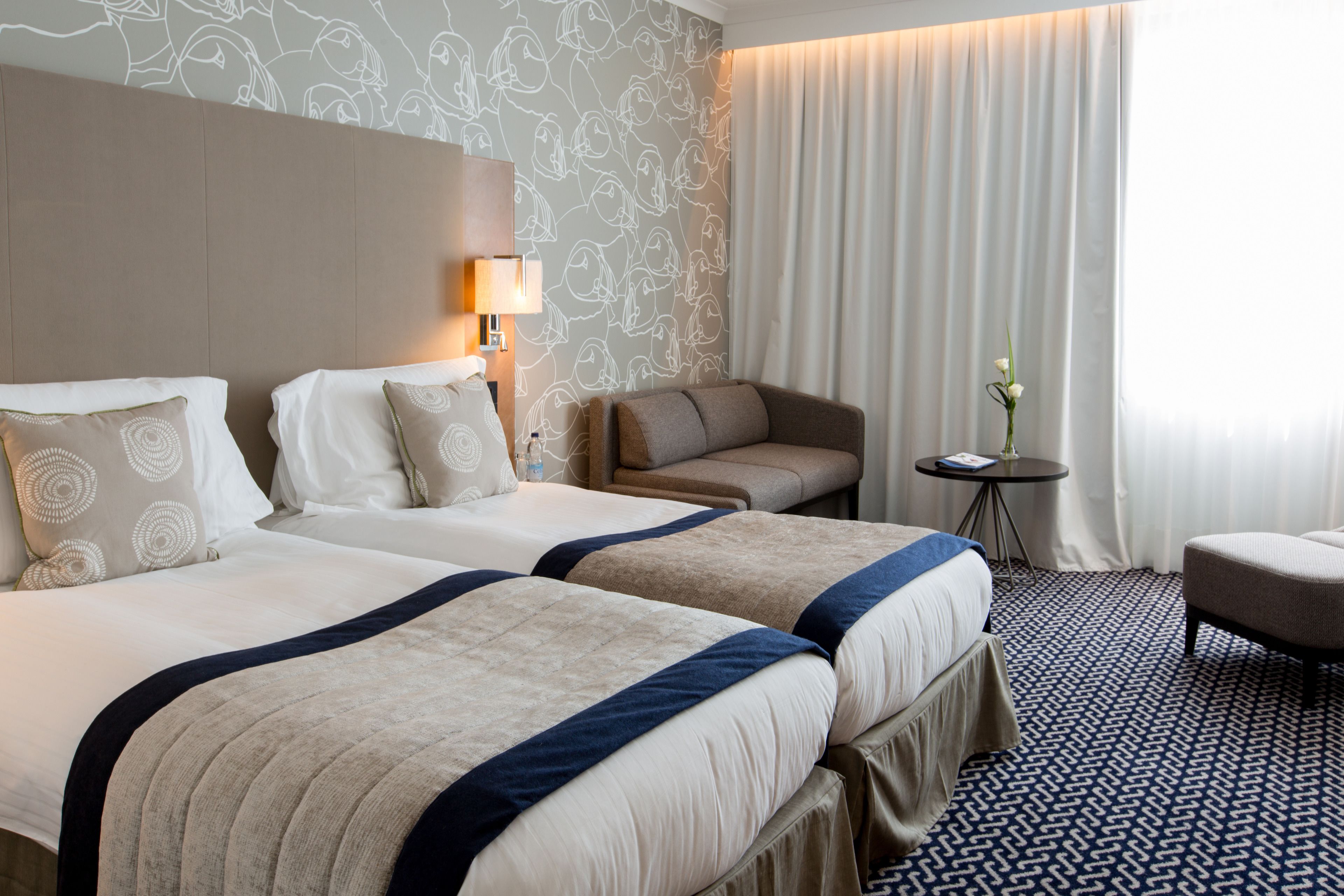 Habitación de hotel con dos camas, un sofá, una mesita y una silla.