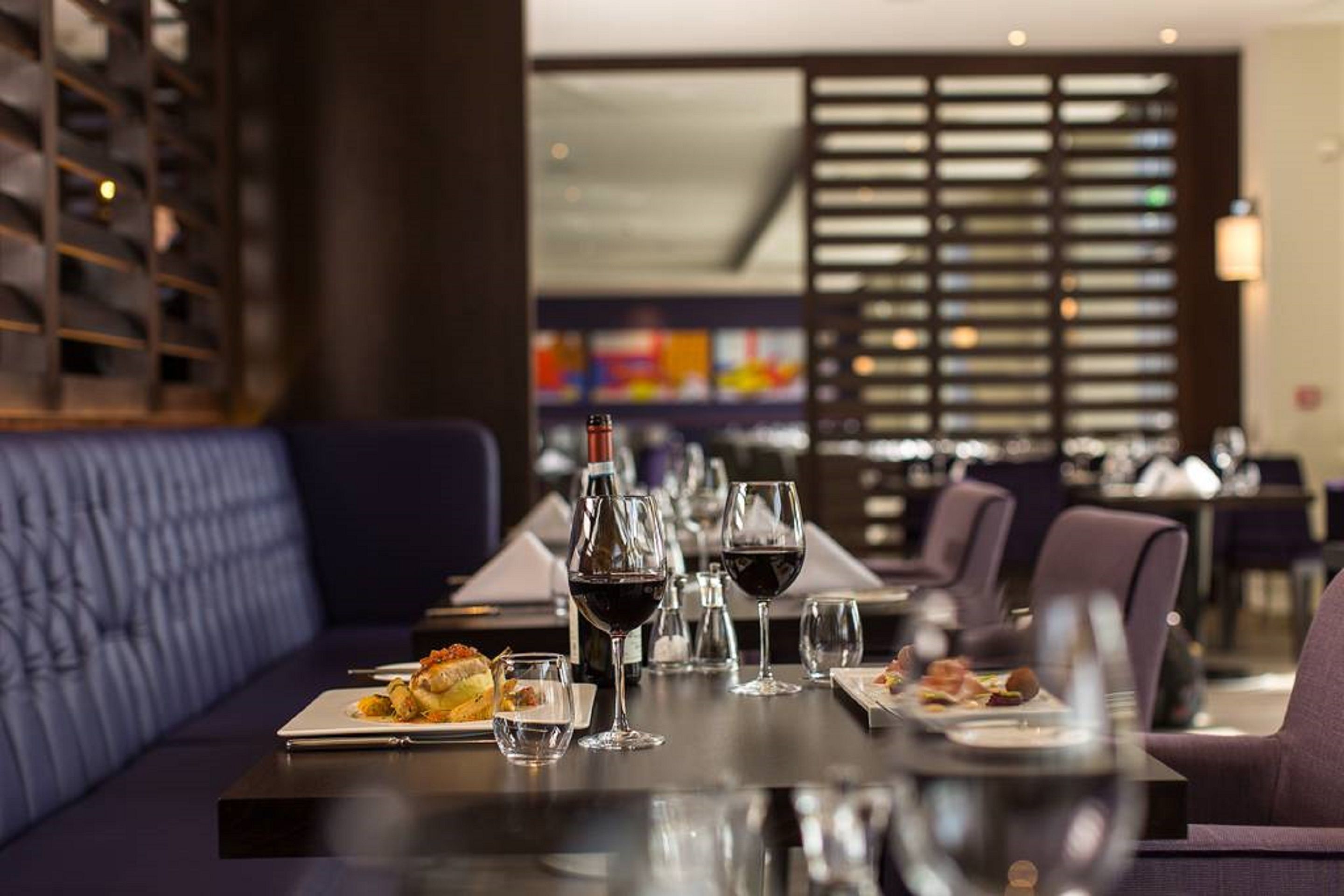 A restaurant with a long table set for dining, wine glasses, and plates of food.