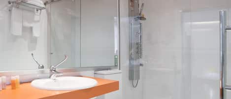 Une salle de bain moderne avec une douche à parois de verre, un lavabo blanc doté d’un plan de toilette orange et des toilettes.