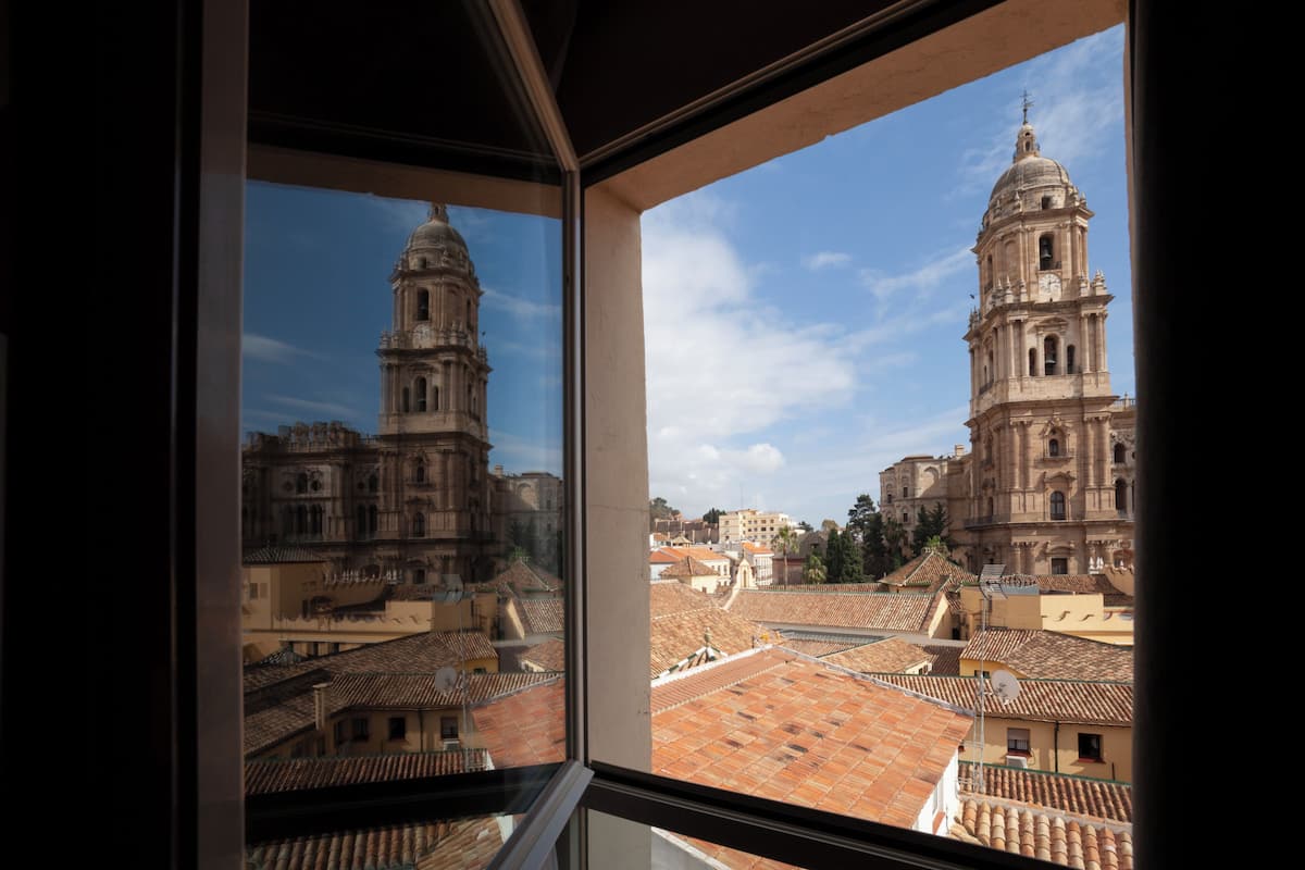 A view from a window of a building with two prominent towers and a tiled roof.