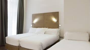Una cama doble con cabecera de madera y dos mesitas de noche, cada una con una lámpara.