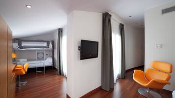 Una habitación de hotel moderna con literas, un televisor de pantalla plana, un escritorio con silla y un ventanal con cortinas.