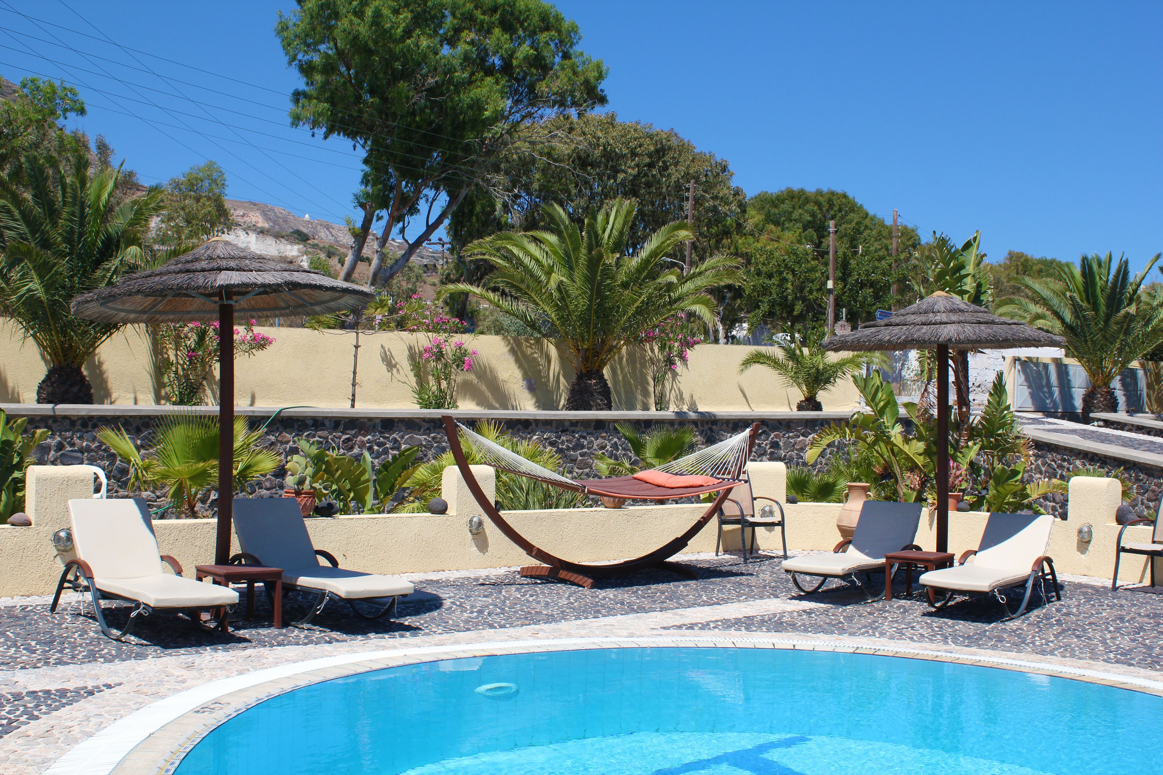 A poolside area with lounge chairs, a hammock, and umbrellas.