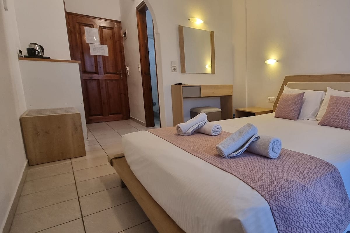 Une chambre d’hôtel avec un grand lit, une tête de lit en bois, deux tables de chevet et un miroir au mur.