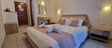 A hotel room with a large bed, a wooden headboard, two bedside tables, and a mirror on the wall.