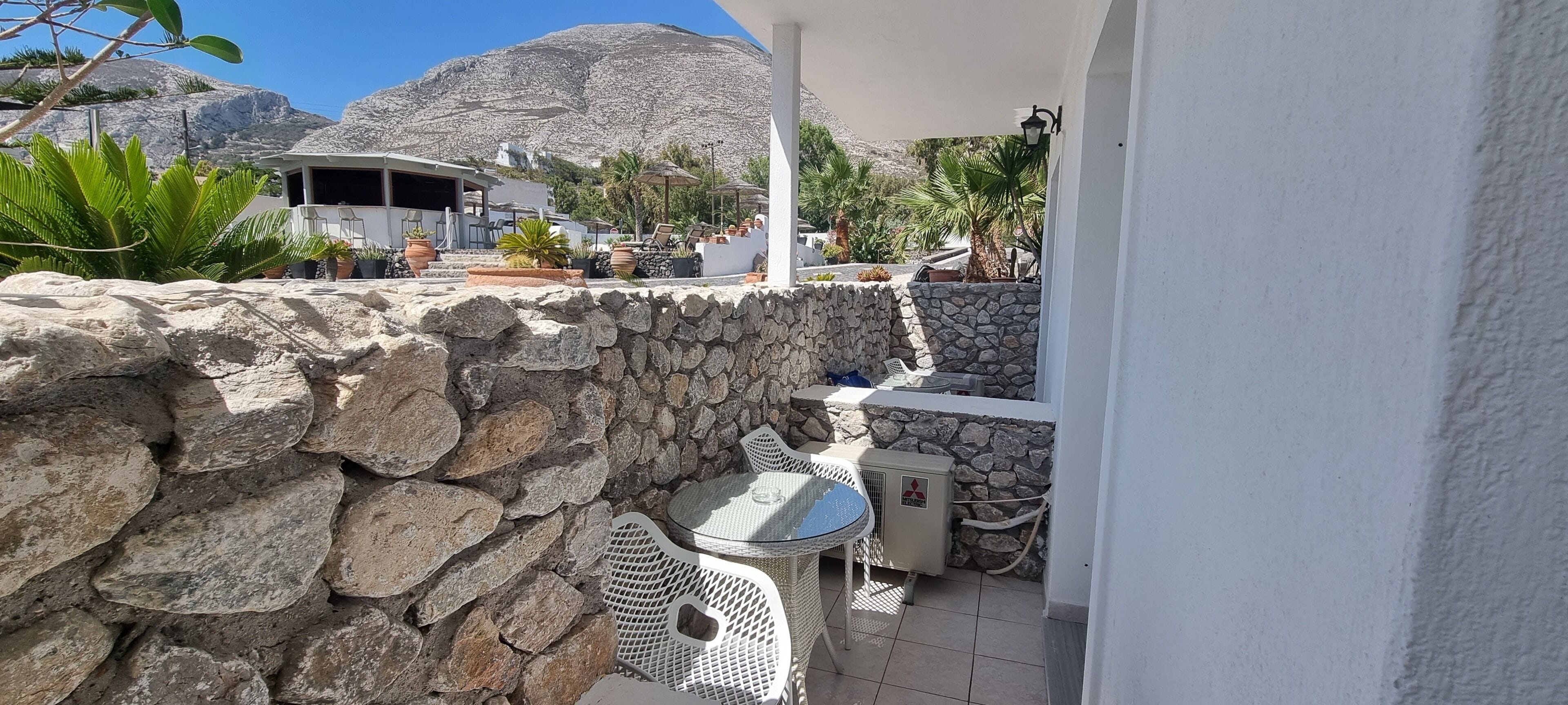 A stone wall, a white building, and a mountain in the background.