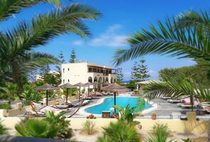 Una piscina al aire libre, sombrillas, sillones reclinables de piscina