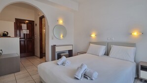 Habitació d'hotel amb un llit gran, dues taules de nit, una tauleta, un mirall i un petit escriptori amb una paperera.