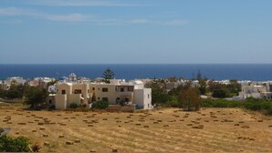 Un poble costaner amb edificis blancs, un camp de farolls i el mar al fons.