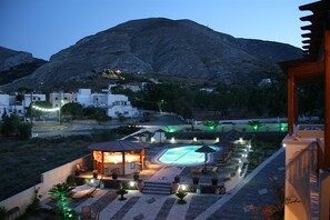 A resort with a swimming pool, outdoor seating, and a mountain backdrop. - Horizon Resort (Santorini)