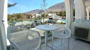 Terrassa amb caires de metall blanc i taules, una piscina i vista a un paisatge de muntanyes.