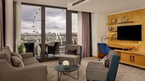 A modern living room with a large TV, comfortable seating, and a view of a Ferris wheel. - Park Plaza County Hall London (London)