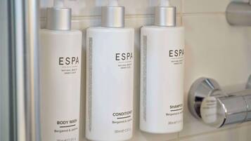 Drei Flaschen ESPA Duschgel, Conditioner und Shampoo in einem Badezimmer.