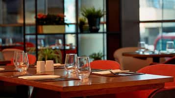 Una mesa de restaurante dispuesta con vasos, cubiertos y servilletas.