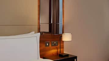 Una habitación de hotel con una cama, una mesita de noche, una lámpara y un espejo.