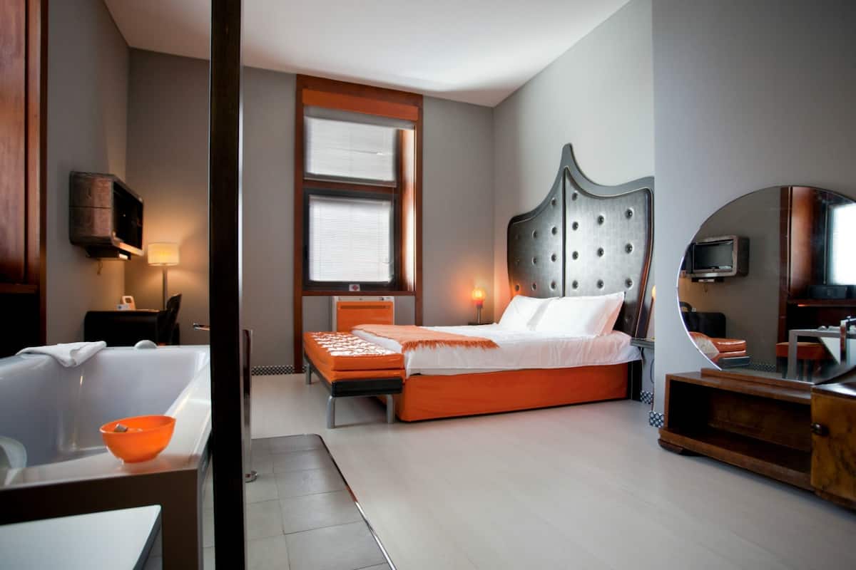 Een moderne hotelkamer met een groot bed, een badkuip en een televisie.