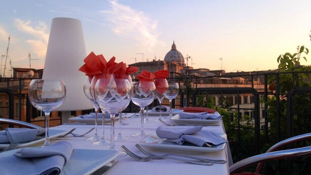 A table set for dining with a view of a cityscape in the background. - Orange Hotel (Rome)