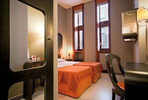 Una habitación de hotel con dos camas, un escritorio y una silla.