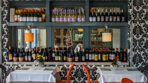 A restaurant with a wine display and two tables with orange chairs. - Orange Hotel (Rome)