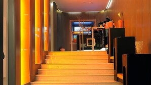 A staircase with a modern design, leading to a room with a large mirror and a vase with flowers. - Orange Hotel (Rome)