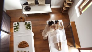 A room with a massage table, a small table with a tray of tea, and a wooden floor. - Sofitel Luang Prabang (Luang Prabang)