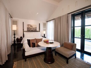 A hotel room with a bed, a round table, a chair, and a view of the outdoors through a large window. - Sofitel Luang Prabang (Luang Prabang)