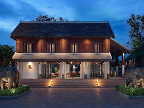 A large wooden house with a covered porch, steps leading to the entrance, and two elephant statues on either side. - Sofitel Luang Prabang (Luang Prabang)