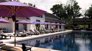 Una piscina al aire libre, sombrillas, sillones reclinables de piscina