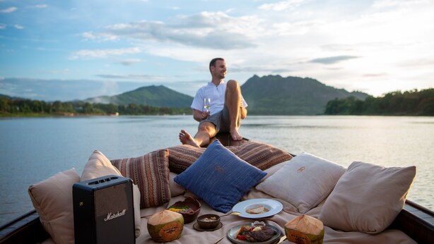 A person relaxing on a boat with a view of a lake and mountains. - Sofitel Luang Prabang (Luang Prabang)
